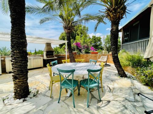 a patio with a table and chairs and palm trees at Out of Africa Resort in Had Nes