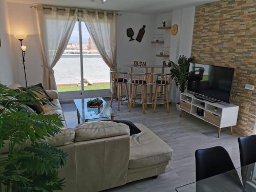 a living room with a couch and a television at Ático 4 dormitorios cerca de la playa con gran terraza y 2 parkings in Roquetas de Mar