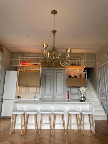 eine Küche mit einer weißen Theke und einem Kronleuchter in der Unterkunft Appartement de charme dans château du XIXème in Lentilly