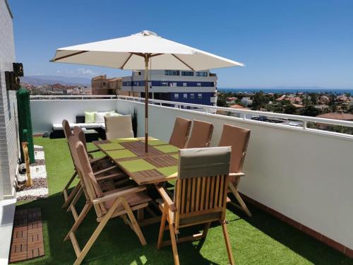 a table and chairs with an umbrella on a balcony at Ático 4 dormitorios cerca de la playa con gran terraza y 2 parkings in Roquetas de Mar