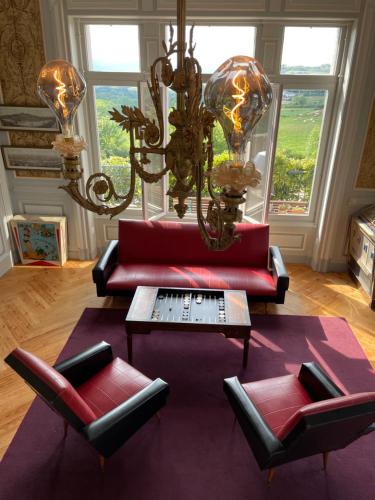 ein Wohnzimmer mit einem roten Sofa und 2 Stühlen in der Unterkunft Appartement de charme dans château du XIXème in Lentilly