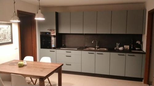 a kitchen with white cabinets and a wooden table at Appartamento Dellantonio in Predazzo