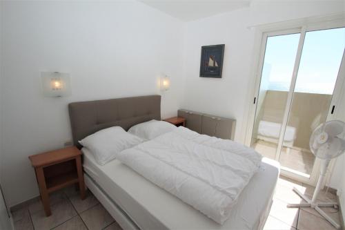 une chambre avec un lit avec des draps blancs et une fenêtre dans l'établissement Appartement 2 pieces en front de mer, à Canet
