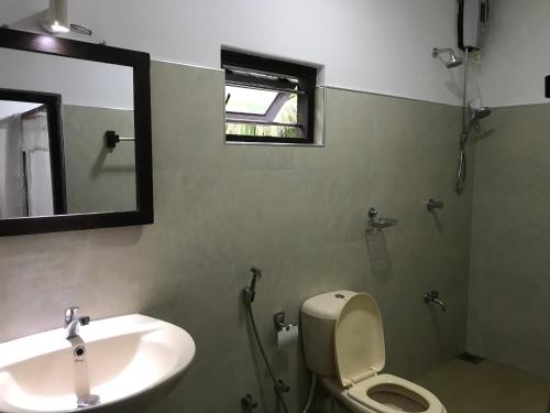 une salle de bain avec un lavabo, des toilettes et un miroir dans l'établissement Mallika Guest House, à Tangalle