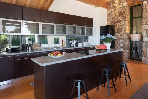 a kitchen with a large island with bar stools at AGROLOGY LUX - 4 BEDROOM Luxurious villa on an Agricultural Haven Retreat in Sálakos
