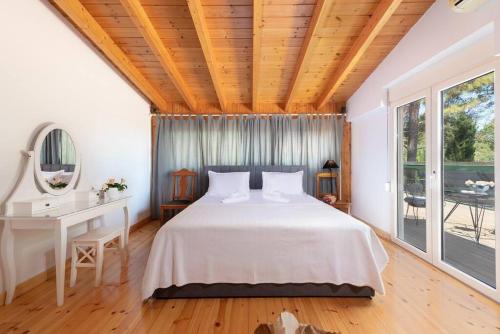 a bedroom with a bed and a desk and windows at AGROLOGY LUX - 4 BEDROOM Luxurious villa on an Agricultural Haven Retreat in Sálakos