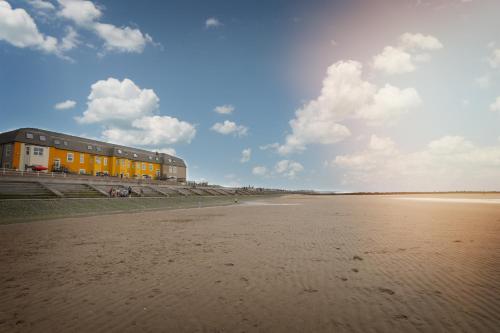 a building on the beach next to a sandy beach at The Beaches Hotel and Spa in Prestatyn