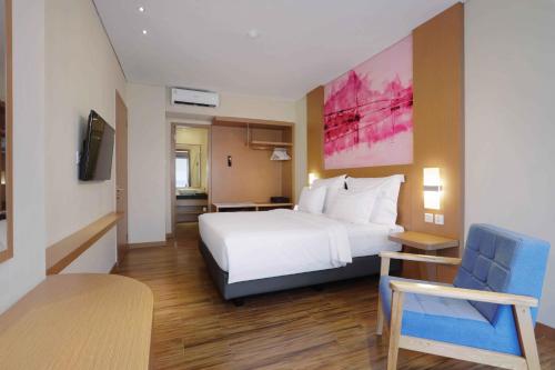 a hotel room with a white bed and a chair at favehotel Nagoya - Batam in Batam Center