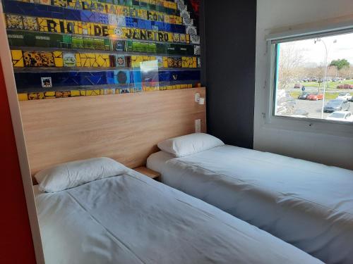 Tempat tidur dalam kamar di Kyriad Direct Caen Nord Memorial