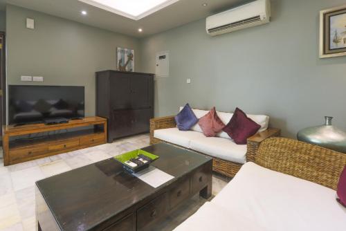 a living room with a couch and a tv at Dar 66 Pool Chalets with Jacuzzi in Ras al Khaimah