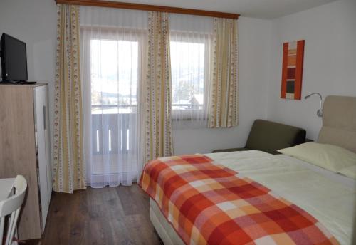 Schlafzimmer mit einem Bett und einem Fenster mit Vorhängen in der Unterkunft Haus Kocher in Haus im Ennstal