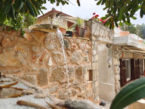 a stone wall with a water fountain at Stone Villa Hvar Ana Nikola Beach Park and Sea View in Jelsa