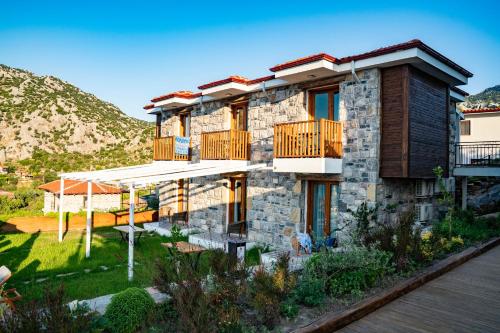 a stone building with balconies and a yard at Alice Tatil Evi in Marmaris