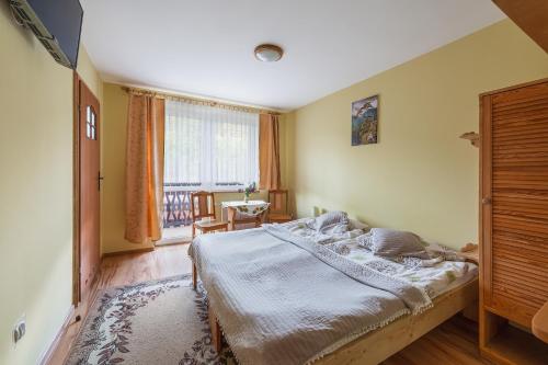 a bedroom with a bed and a table and a window at Pokoje nad Czarną Wodą Agroturystyka in Jaworki