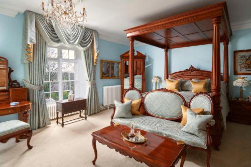 a bedroom with a canopy bed and a coffee table at Plas Dinas Country House in Caernarfon