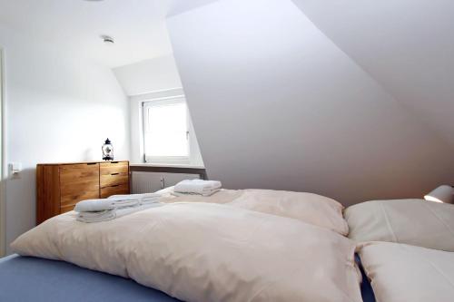 a bedroom with a bed with white sheets and a window at Senhues-App-7 in Hörnum