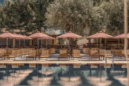 a group of chairs and umbrellas next to a pool at Cook's Club Corfu - Adults Only in Gouvia