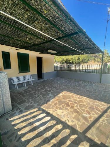 un patio avec un banc blanc sous un toit dans l'établissement Alba Holiday House , Casa Vacanze Ricadi, à Santa Maria