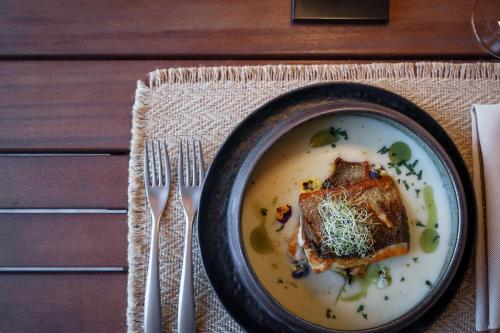 a bowl of soup with a piece of food on a table at Cook's Club Corfu - Adults Only in Gouvia