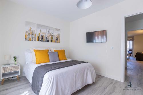 1 dormitorio blanco con 1 cama grande con almohadas amarillas en Living4Malaga Suite Capuchinos Apartment, en Málaga