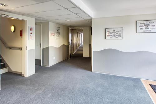 an empty hallway in an office building with a hallway at Hôtel Formules Club in Cenon