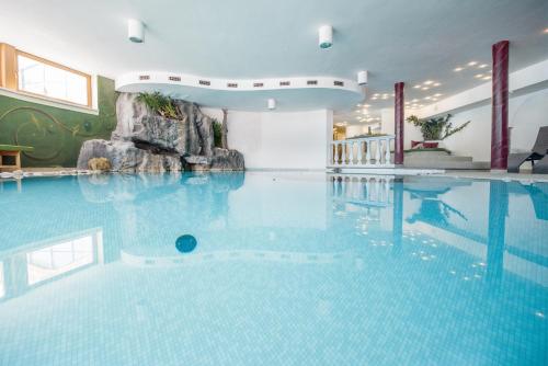 a large pool with blue water in a building at Vierbrunnenhof in Anterselva di Mezzo