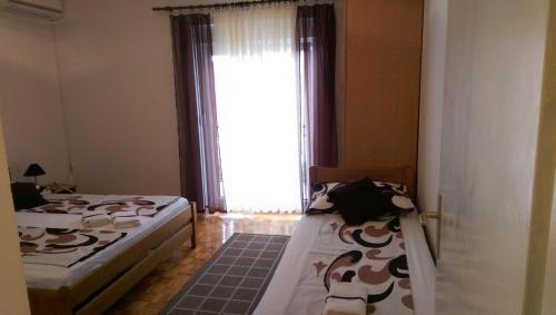 a bedroom with two beds and a large window at Apartmani MILLE in Starigrad