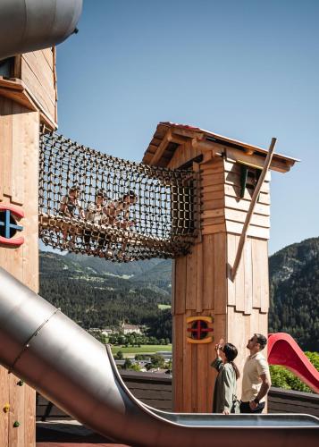 two people standing in a playground with a slide at Falkensteiner Family Resort Lido Superior in Chienes