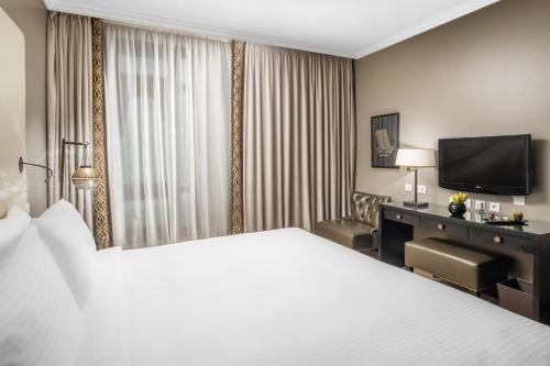 a hotel room with a large bed and a desk at Sofitel Shahd Al Madinah in Al Madinah