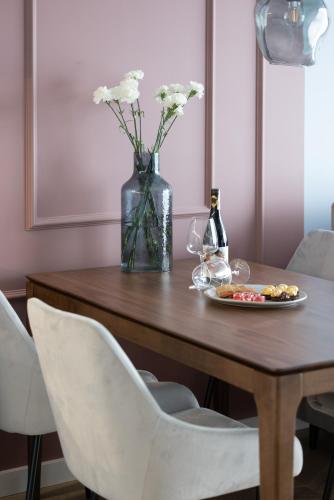 a table with a vase of flowers and a bottle of wine at Apartamenty The View Hevenia in Rewal