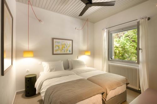 a bedroom with a bed with white sheets and a window at Paleokastritsa Red Gate Flat in Paleokastritsa