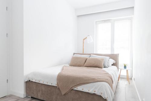 - une chambre avec un lit aux murs blancs et une fenêtre dans l'établissement Apartment City Centre Netflix- GreenPark - River, à Olsztyn
