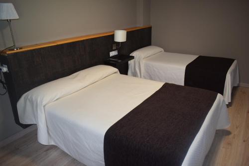 2 bedden in een hotelkamer met wit en zwart bij Hotel Juan Canejan in Les