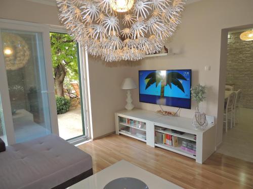 a living room with a tv and a chandelier at Apartment Ferara in Betina