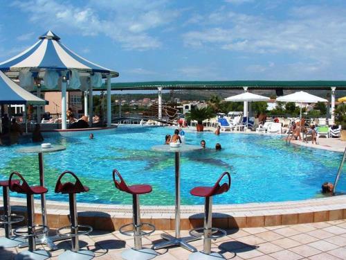a pool with chairs and people in the water at Apartment 3a, first floor in Rogoznica