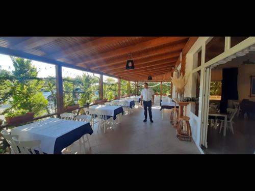 a man walking on a porch with tables and chairs at Apartment 3a, first floor in Rogoznica