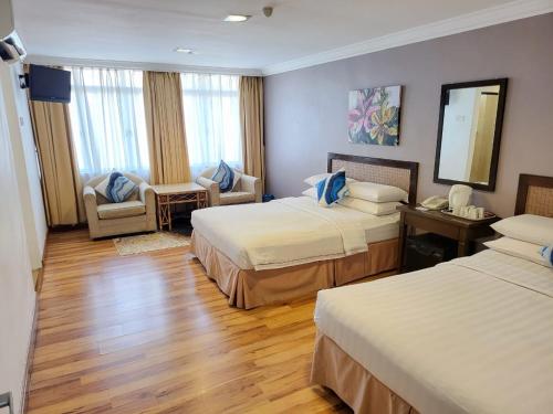 a hotel room with two beds and a mirror at Queenspark Lovita Hotel in Melaka