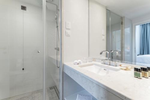 a white bathroom with a sink and a shower at Riva Marina Hvar Hotel in Hvar
