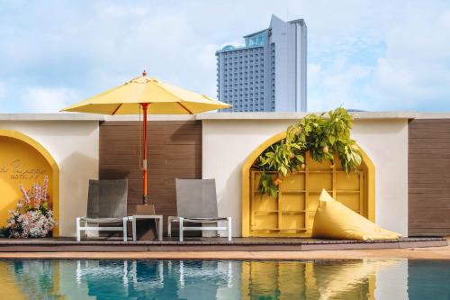 a pool with chairs and an umbrella next to a building at Grand Palazzo Hotel - SHA Extra Plus in Pattaya