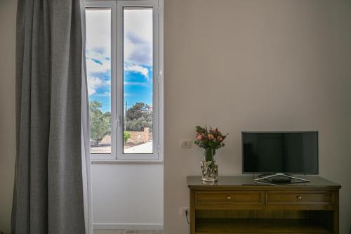 a television sitting on a dresser next to a window at Dimora Savarino Marzamemi Suites with pool in Marzamemi