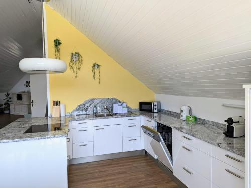 a kitchen with white cabinets and a yellow wall at Rheinquartier Küssaberg Rheinheim in Küssaberg