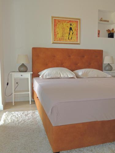 a bedroom with a bed with a wooden headboard and a table at Apartment Ferara in Betina