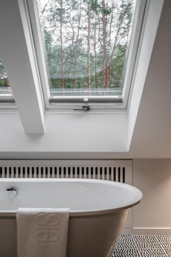 a window above a bathtub in a bathroom with a window at ESE HOTEL in Birštonas