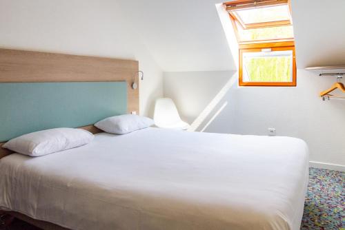 a bedroom with a large white bed with a window at Hôtel REVOTEL Nancy Centre Gare et Congrès in Nancy