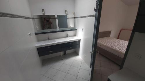 une salle de bain avec un lavabo, un lit et un miroir dans l'établissement Agréable maison spacieuse à la Tremblade, à La Tremblade