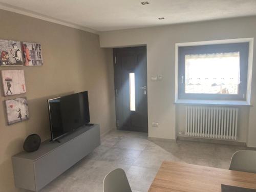a living room with a flat screen tv and a window at Senin House in Aosta