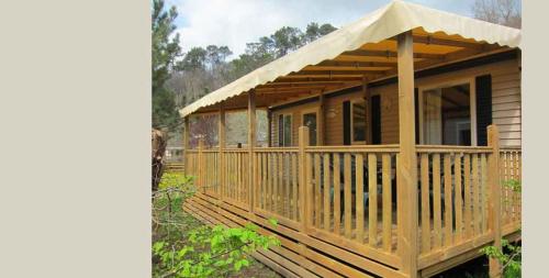 a wooden cabin with a porch and a deck at Camping le Moulin de David -Gaugeac Monpazier 24540 - Cabane -Mobil-home 3 et 2 chambres in Gaugeac