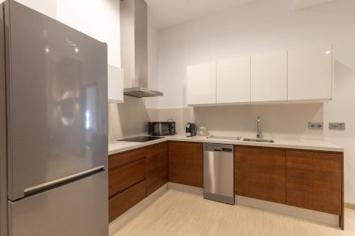 a kitchen with a stainless steel refrigerator and wooden cabinets at BiBo Suites San Agustín in Granada