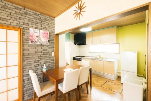 uma cozinha com uma mesa de madeira e cadeiras brancas em 旭川美瑛 Sakura 西神楽 em Asahikawa
