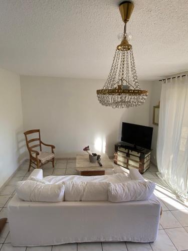 a living room with a white couch and a chandelier at Grand appartement en résidence calme avec piscine in Saint-Paul-lès-Dax